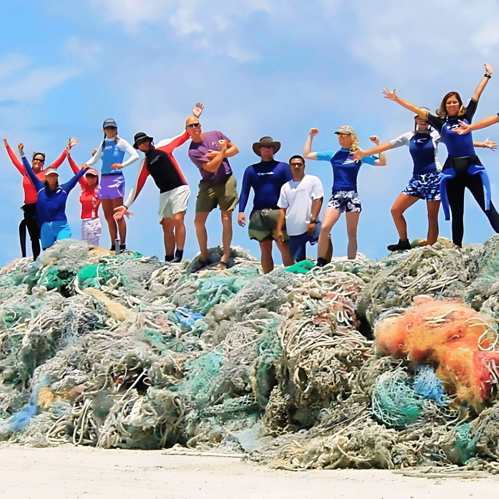 NOAA divers stand on a pile of nets they removed in Hawaii, celebrating the removal of derelict marine debris (Credit: NOAA)