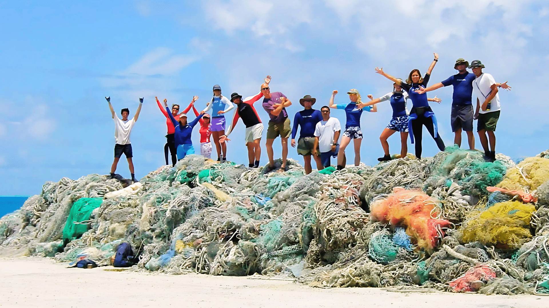 NOAA divers stand on a pile of nets they removed in Hawaii, celebrating the removal of derelict marine debris (Credit: NOAA)