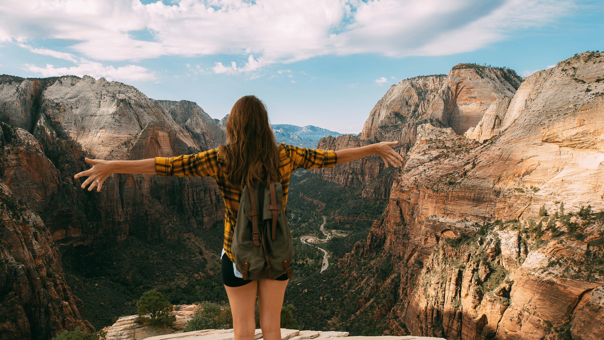Person with their hands up standing on top of mountain