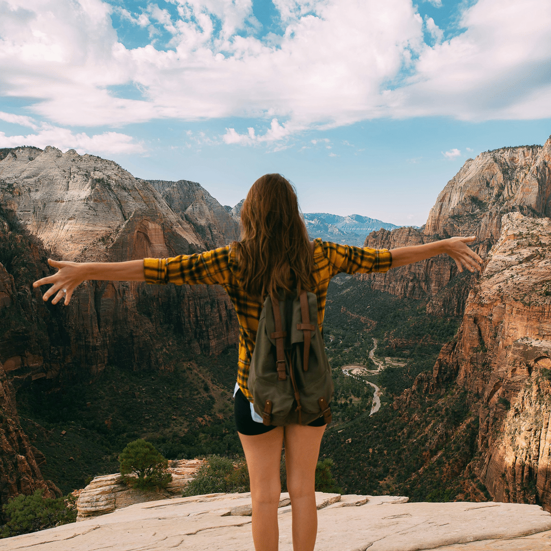 Person with their hands up standing on top of mountain