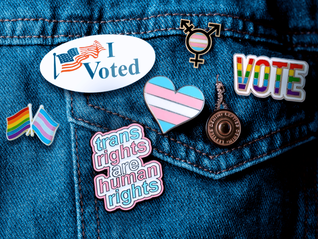 Transgender advocate with 'I voted' sticker, 'Trans rights are human rights' pin