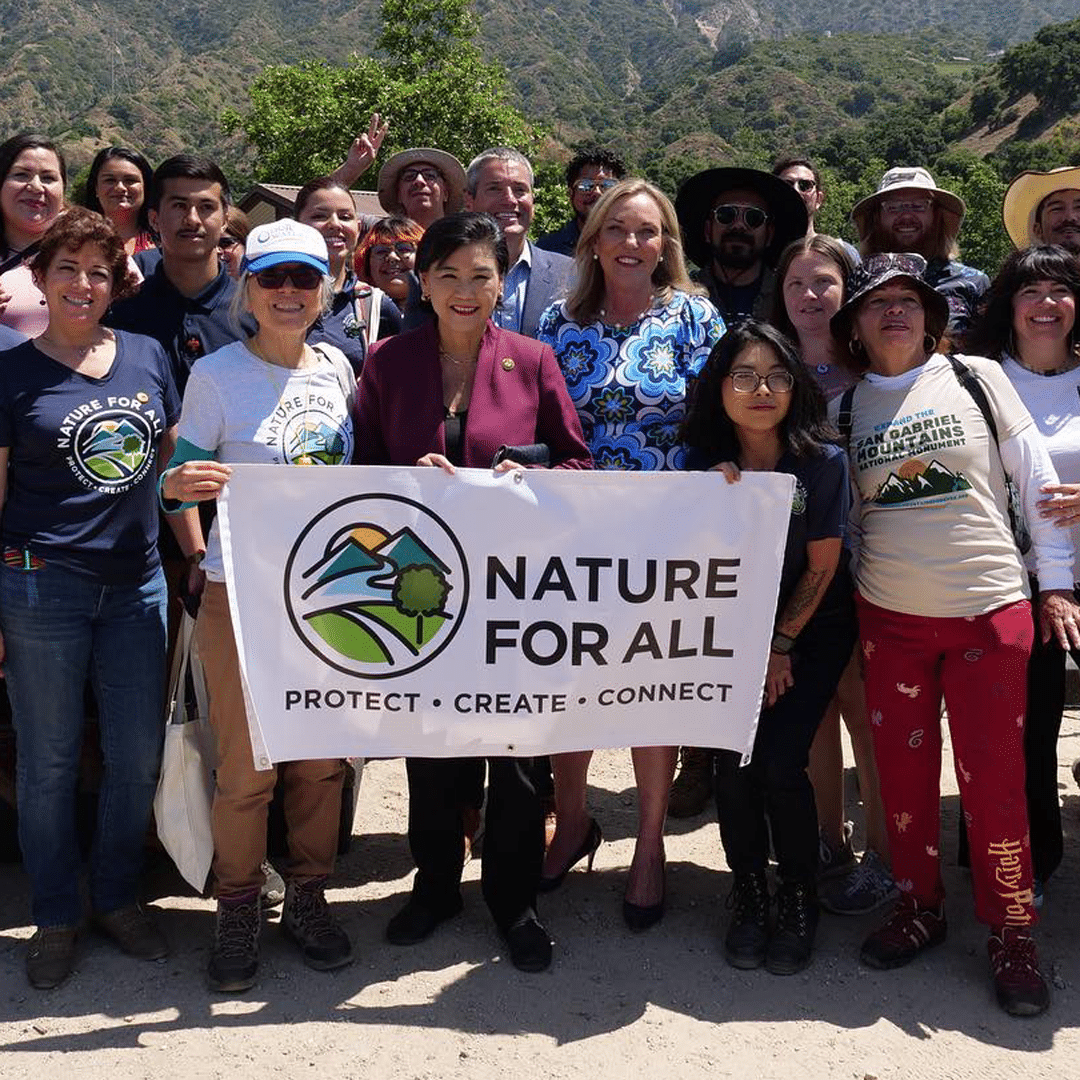 Group at hike holding up sign with Nature for All logo