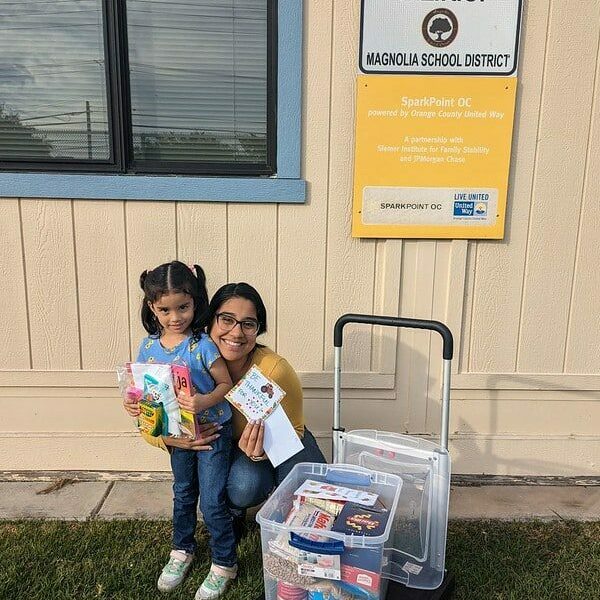 Young woman and child holding children's books gifted through a supply drive