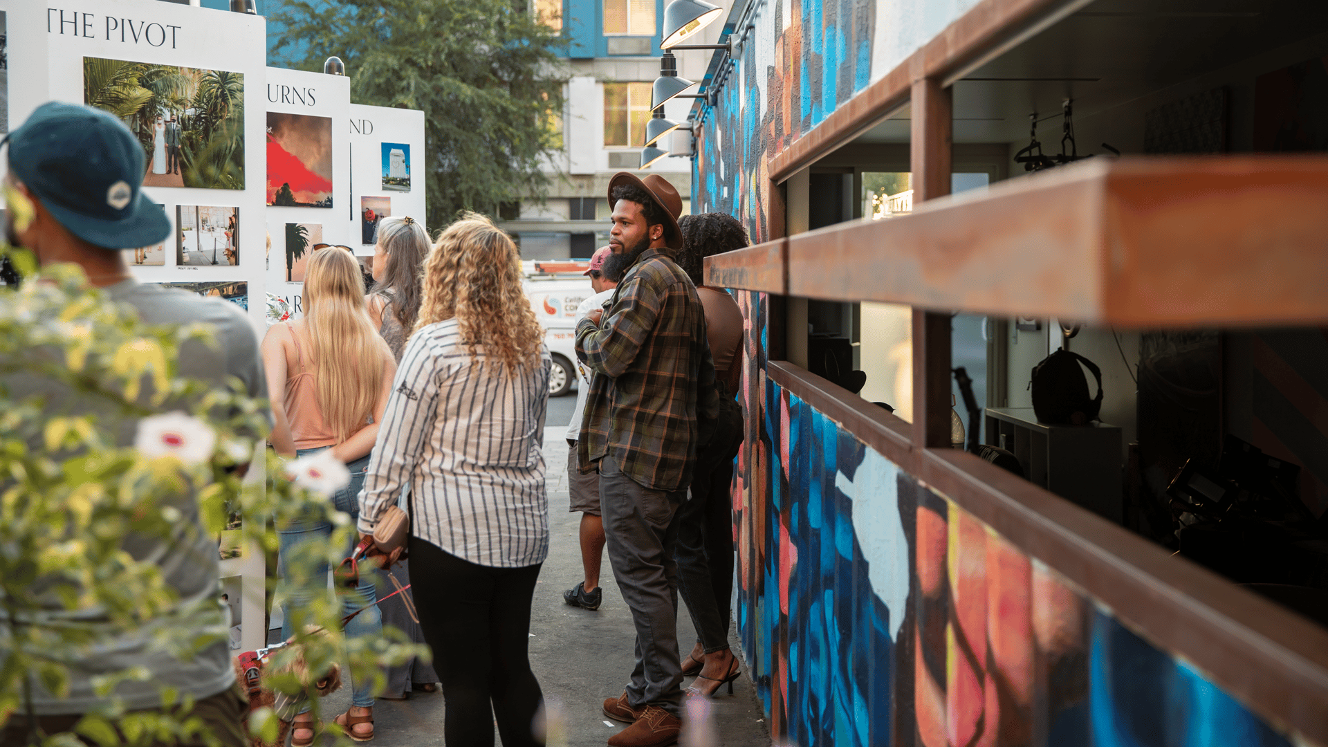 People looking at outdoor display of photographs on a installation wall at San Diego Design Week