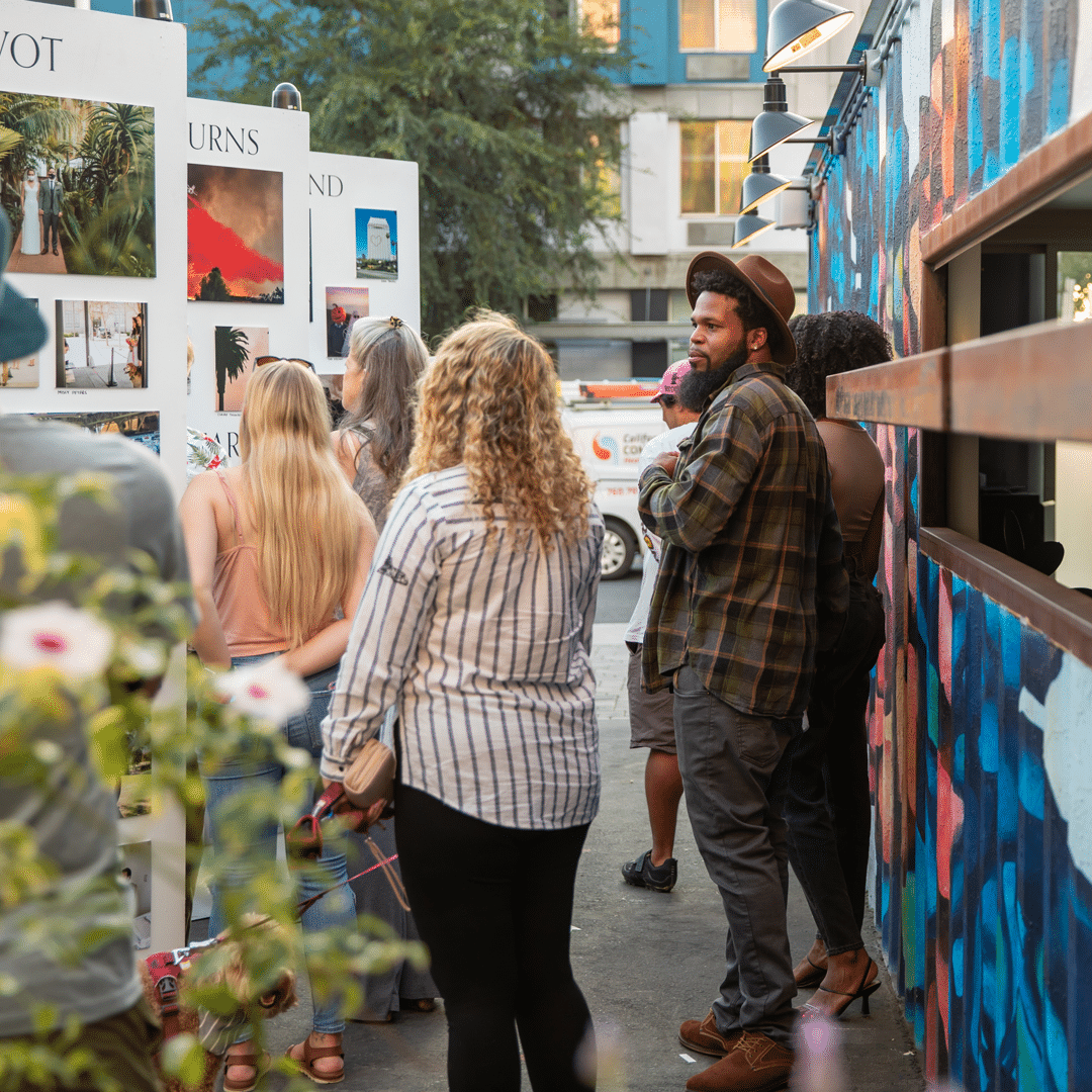 People looking at outdoor display of photographs on a installation wall at San Diego Design Week