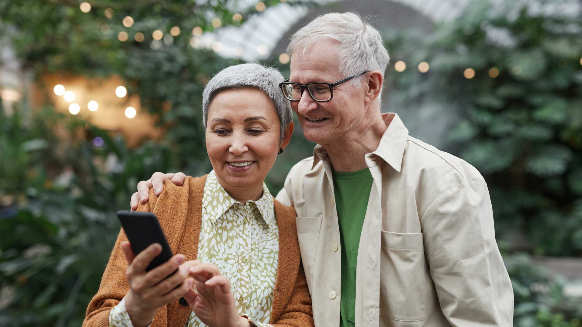 Two elderly smiling and looking at phone together