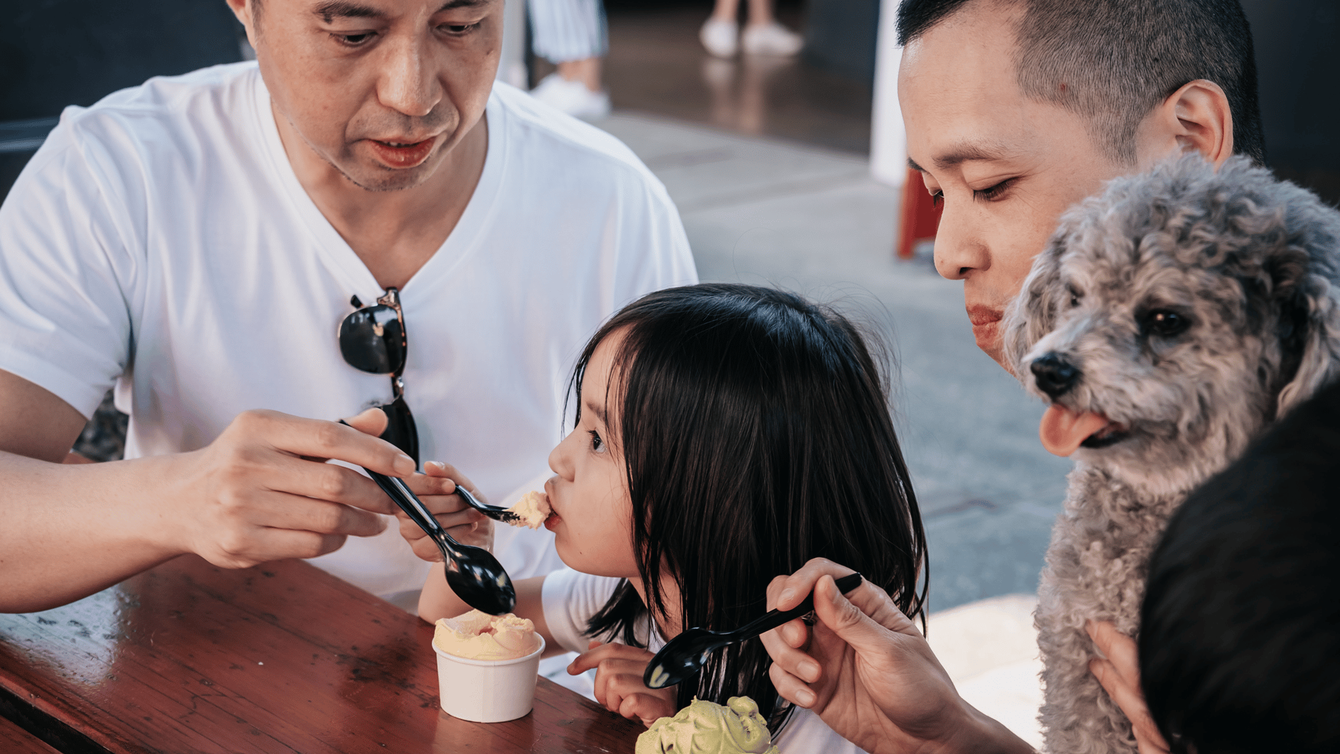 Family eating ice cream with child and dog at table