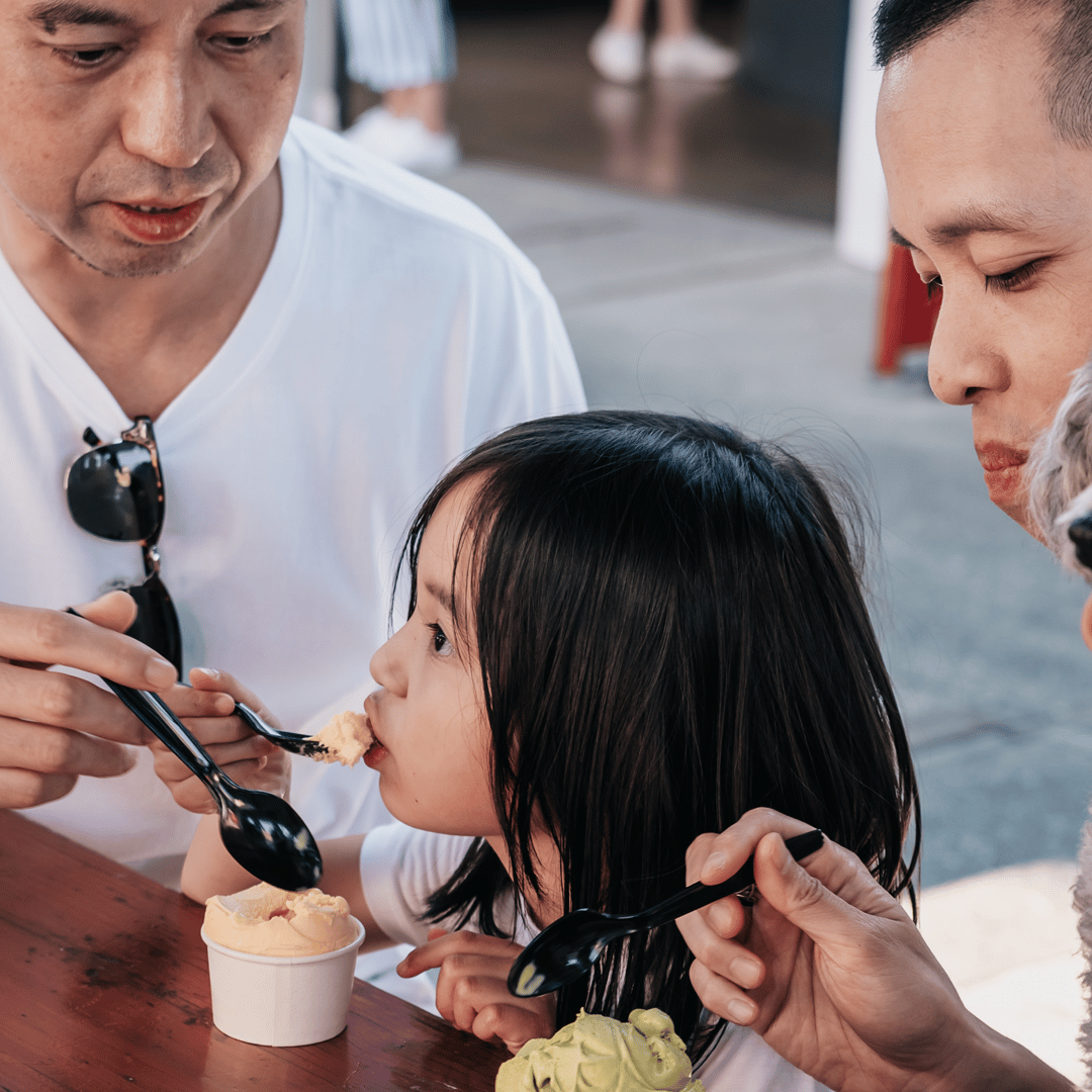 Family eating ice cream with child and dog at table