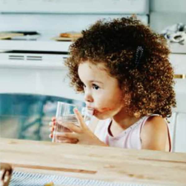Child drinking water in kitchen