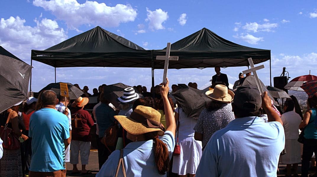 People surrounding a tent holding a cross